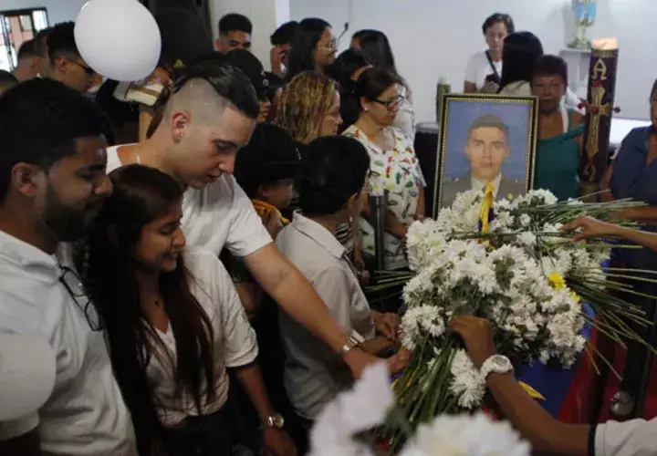  Familiares y amigos se acercan al ataúd del cadete Juan Esteban Marulanda durante su velorio, celebrado este lunes en la Escuela de Policía Carlos Holguín. FOTO/EFE