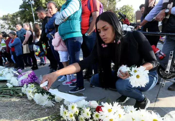 Decenas de personas llevan flores y prenden velas en honor a los policías fallecidos en el ataque de ayer en la Escuela de Cadetes de Policía General Francisco de Paula Santander, en Bogotá. FOTO/EFE