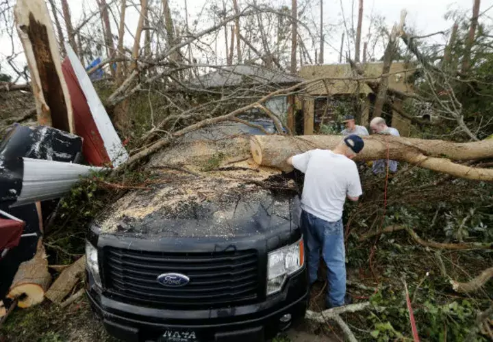 La gente corta un árbol que cae en un vehículo después del huracán Michael en la ciudad de Panamá, Florida. AP 