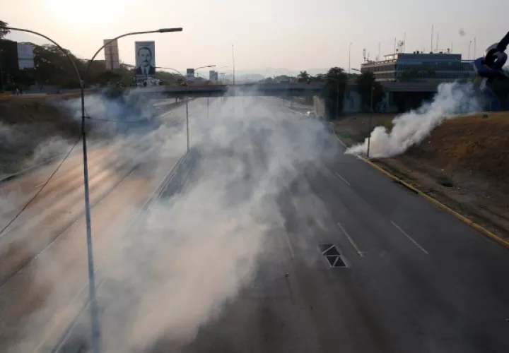 El gas lacrimógeno cubre una carretera vacía junto a la base aérea La Carlota en Caracas. FOTO/AP