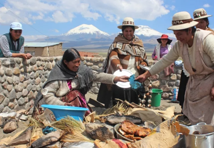Mujeres de la comunidad Sajama preparando un plato de comida cocinado debajo de la tierra.  EFE/Yolanda Salazar