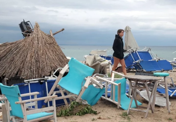 Una mujer camina entre sillas y paraguas que los fuertes vientos y el agua arrasaron en Sozopolis, Chalkidiki, norte de Grecia. FOTO/AP