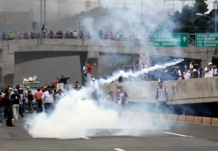 Personas se enfrentan  a efectivos de la Policía hondureña en el segundo día de paro nacional, en Tegucigalpa. EFE