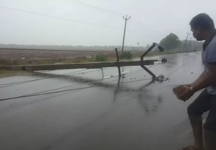 Un hombre sostiene un ladrillo para construir un desvío de la carretera para ayudar a los carros a evitar un poste eléctrico que cayó después del ciclón Gaja en la India. AP