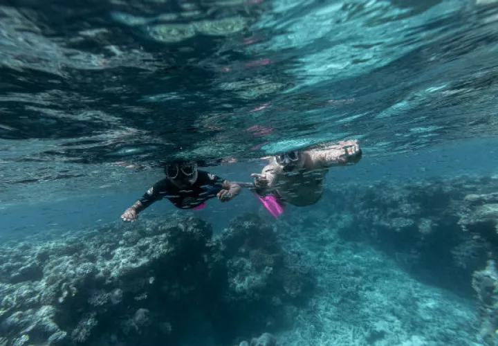 Murrumu de Walubara haciendo snórquel con su hijo en la Gran Barrera de Coral, que, dice, es territorio indígena. Foto/ Brook Mitchell para The New York Times.