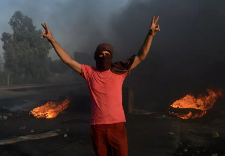 Durante el tiroteo, los manifestantes incendiaron llantas para hacer retroceder a los soldados. Foto: EFE.