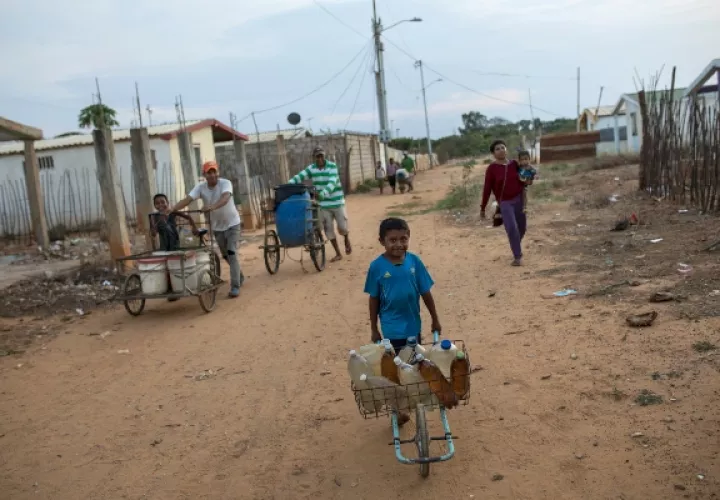 Residentes, jóvenes y viejos, empujan agua potable en el barrio de Villa Esperanza, en las afueras de Maracaibo. FOTO/AP