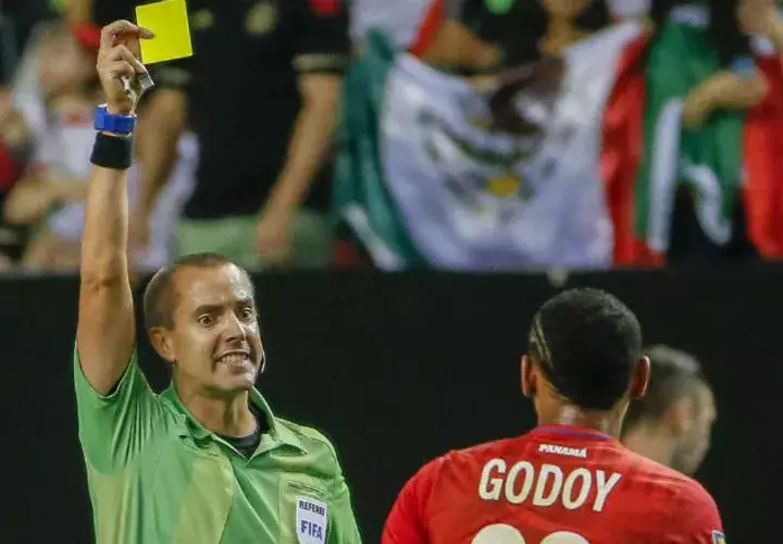 El árbitro Mark Geiger muestra tarjeta amarilla a Anibal Godoy. Foto:EFE 