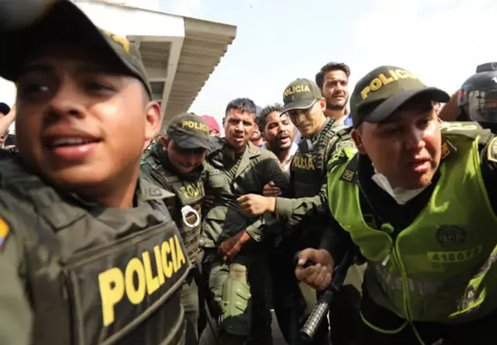 La policía colombiana escolta a un soldado venezolano que se rindió en el puente internacional Simón Bolívar. FOTO/AP