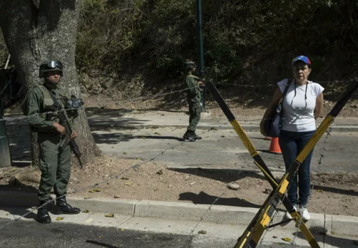 Una mujer está de pie junto a los soldados mientras otros miembros de la oposición entregan copias de una ley de amnistía cerca de Ft. La base militar de Tiuna en Caracas. FOTO/AP
