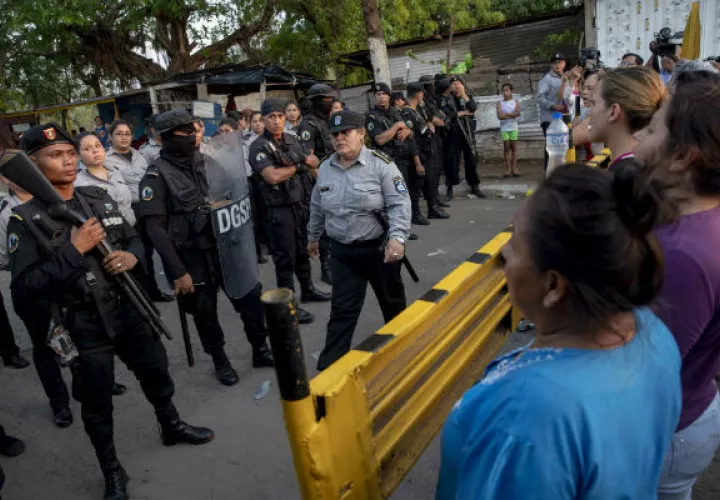 Antimotines de la Policía Nacional (izq) mantenían un cordón de seguridad frente a familiares de presos de la cárcel "La Modelo". Foto: EFE.