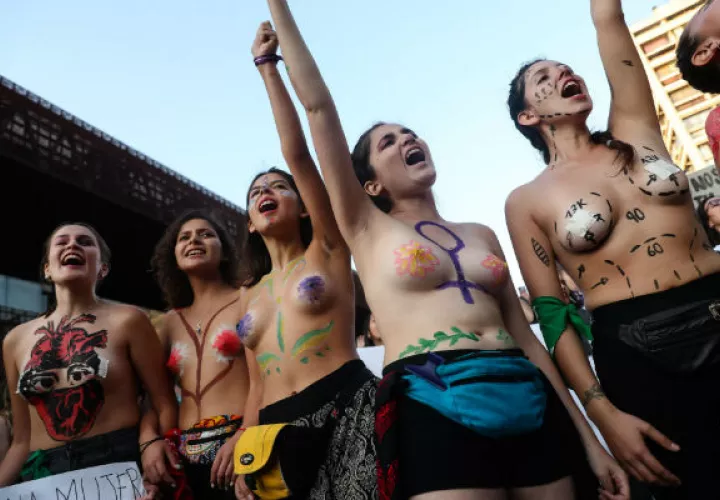 Mujeres con los torsos decorados con pinturas en la Alameda de Santiago, principal avenida de la capital chilena.  Foto: EFE.