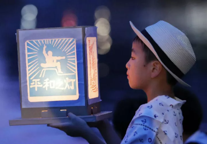 Un niño sostiene una "Luz de Paz" ante el río Urigami en Nagasaki. Foto: AP.