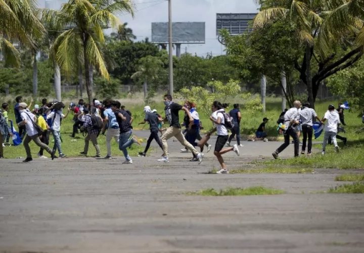 Varios jóvenes corren después que miembros de la policía nacional lanzaran bombas aturdidoras tras ser atacados con piedras por un grupo de manifestantes este domingo, en Managua (Nicaragua). FOTO/EFE
