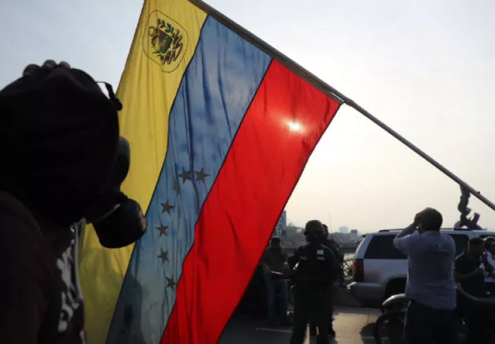 Simpatizantes del presidente interino Juan Guaidó se protegen de las bombas lacrimógenas que las fuerzas de seguridad leales al Gobierno de Nicolás Maduro. Foto/EFE