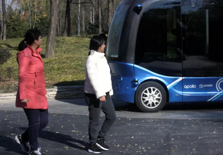 Un pequeño autobús, más alto que largo,  cruza sin pasajeros en su interior y a muy baja velocidad por delante de una marquesina donde esperan los visitantes.  FOTO/EFE