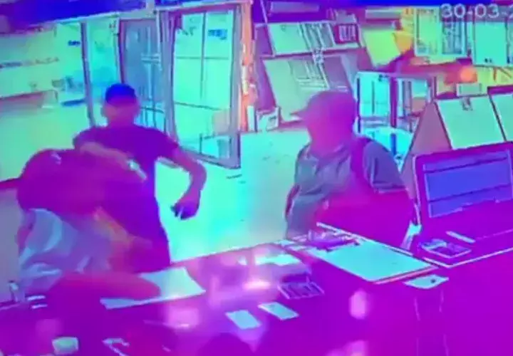 Uno de los delincuentes saca un arma de fuego y apunta directamente a la persona que administraba el local comercial. 