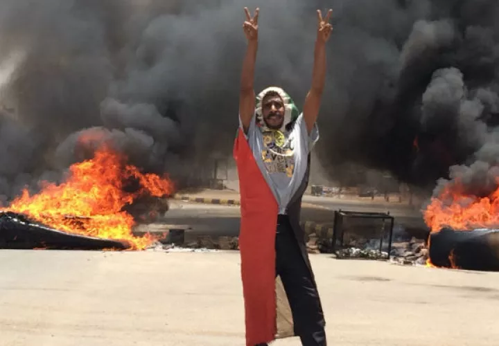 Un manifestante hace la señal de victoria ante neumáticos en llamas en Khartoum, Sudán. Foto: AP.