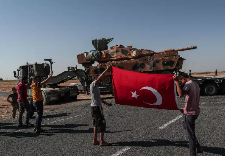 Jóvenes con la bandera turca al paso de blindados militares turcos en el noreste de Siria. Foto: EFE.