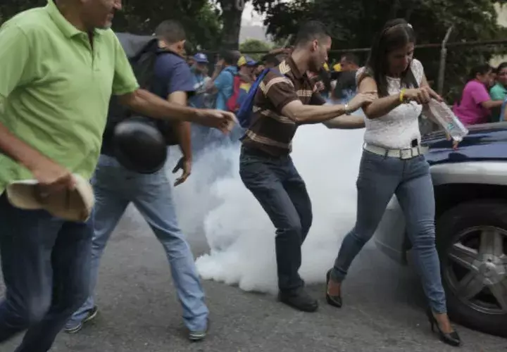 Opositores se alejan del gas lacrimógeno lanzado cerca a la tarima de Guaidó. Foto: AP. 