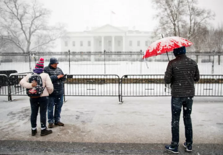 Varias personas contemplan el exterior nevado de la Casa Blanca en Washington D.C (Estados Unidos), durante la tormenta de nieve. Foto: EFE